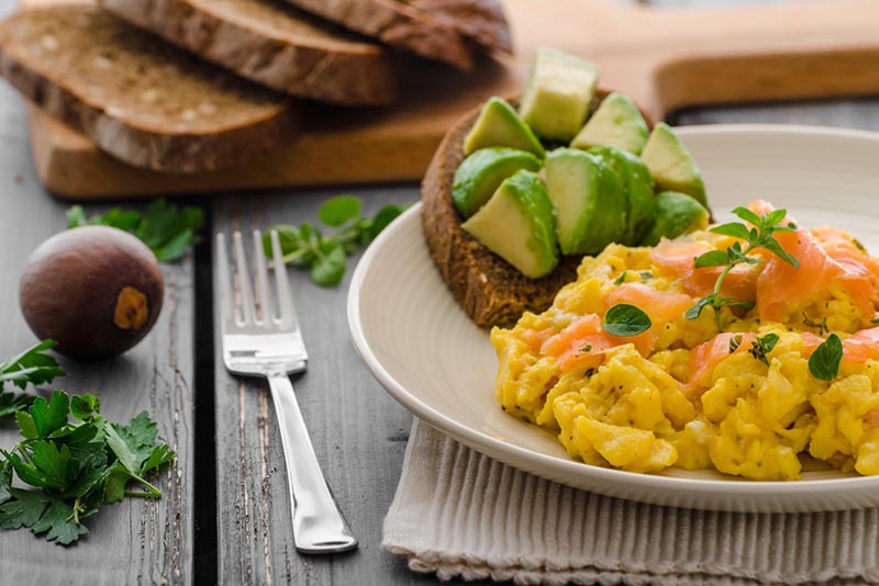 Photo of bred with avocado and scrambled eggs with salmon.