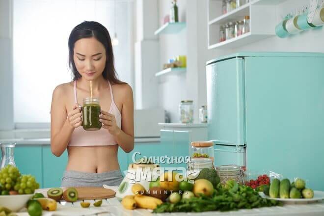 Стройная девушка пьет зеленый коктейль, фото
