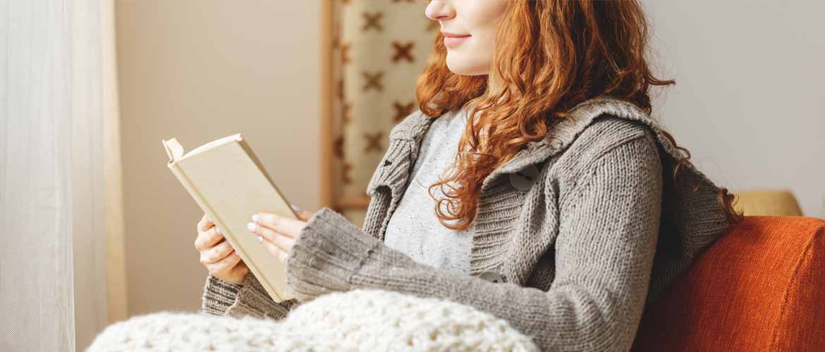 woman sitting on a couch reading a book