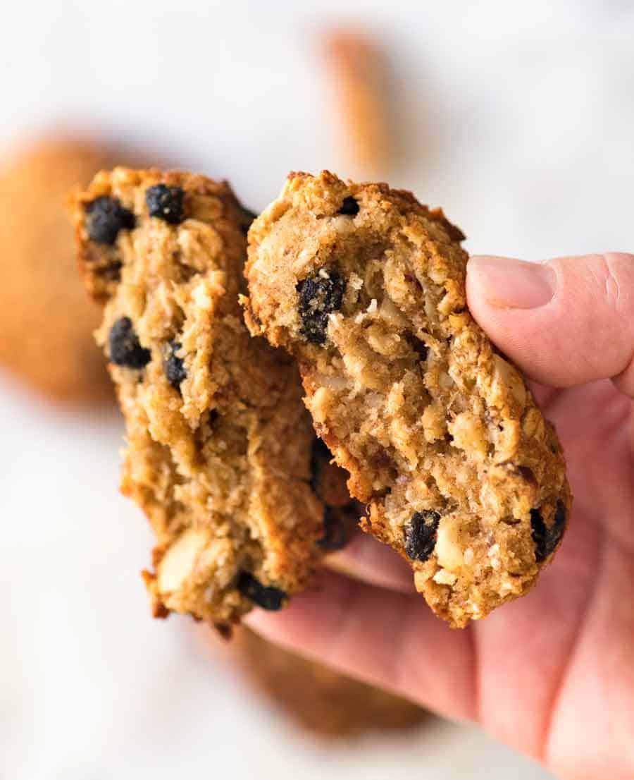 Close up of hand holding Healthy Oatmeal Cookies broken in half to show the chewy inside